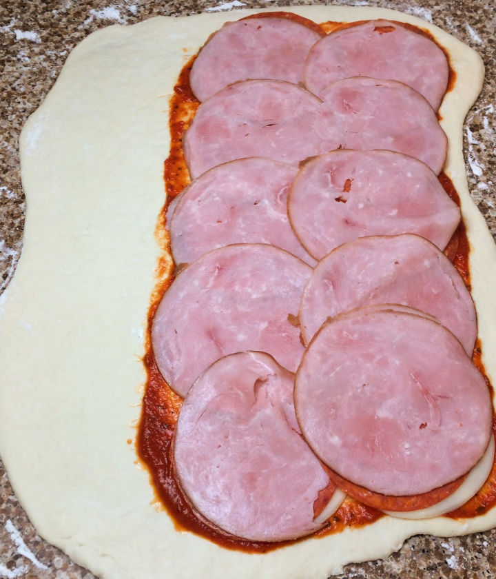 Layer sauce and sliced ham on top of dough