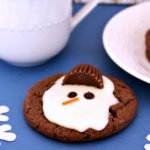 melted snowman cookie sitting beside saucer with mug of milk