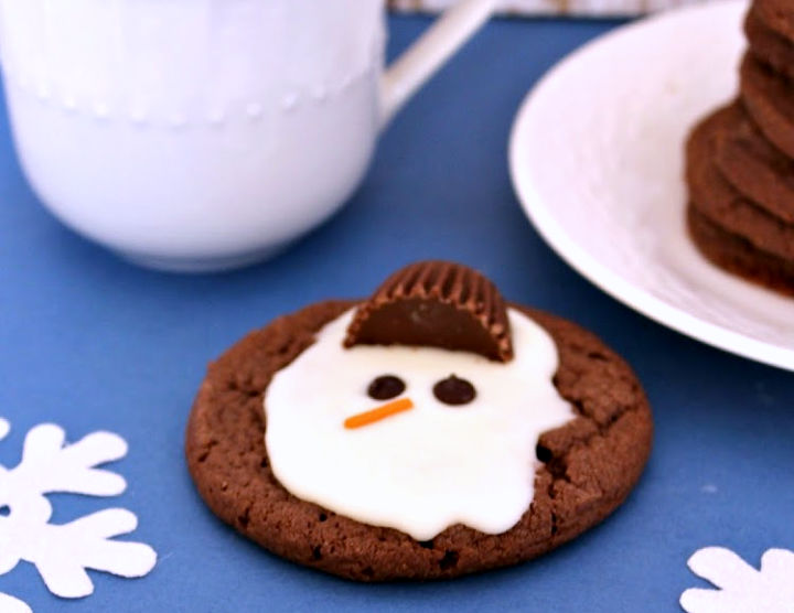melted snowman cookie sitting beside saucer with mug of milk